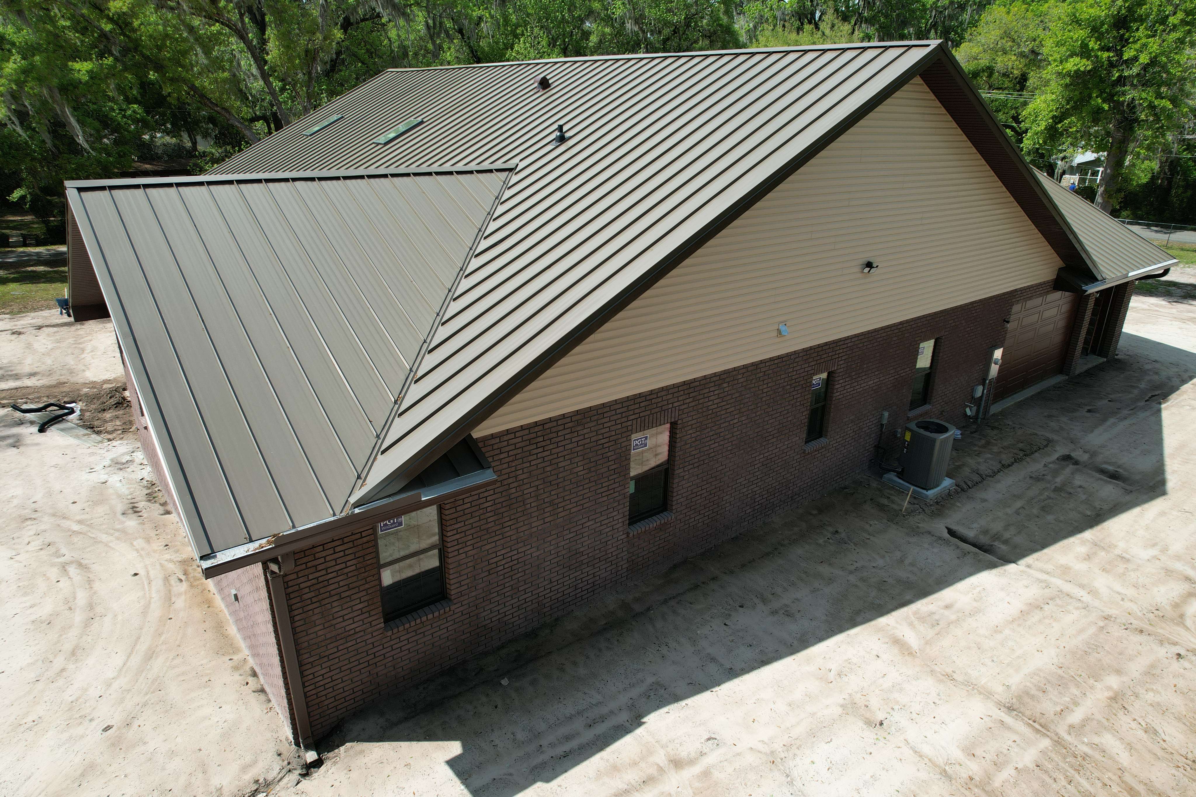 A brown building with a metal roof and a trash can