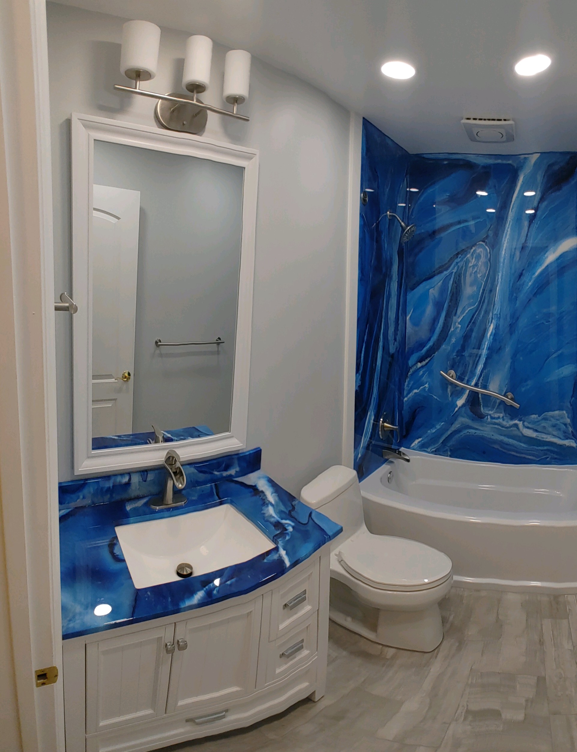 A white and blue bathroom with a tub, toilet and sink