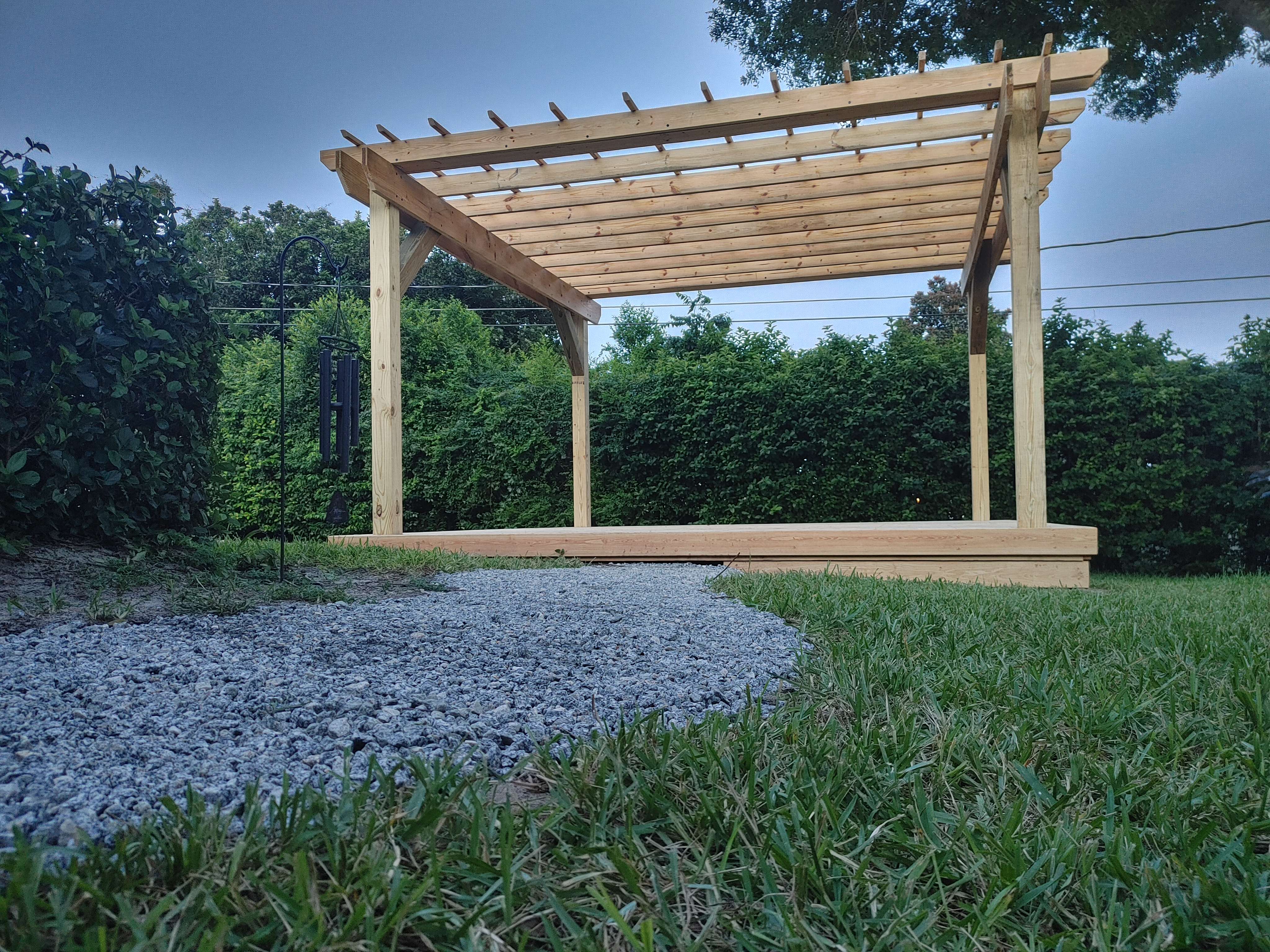 A wooden pergolan sitting in the middle of a field